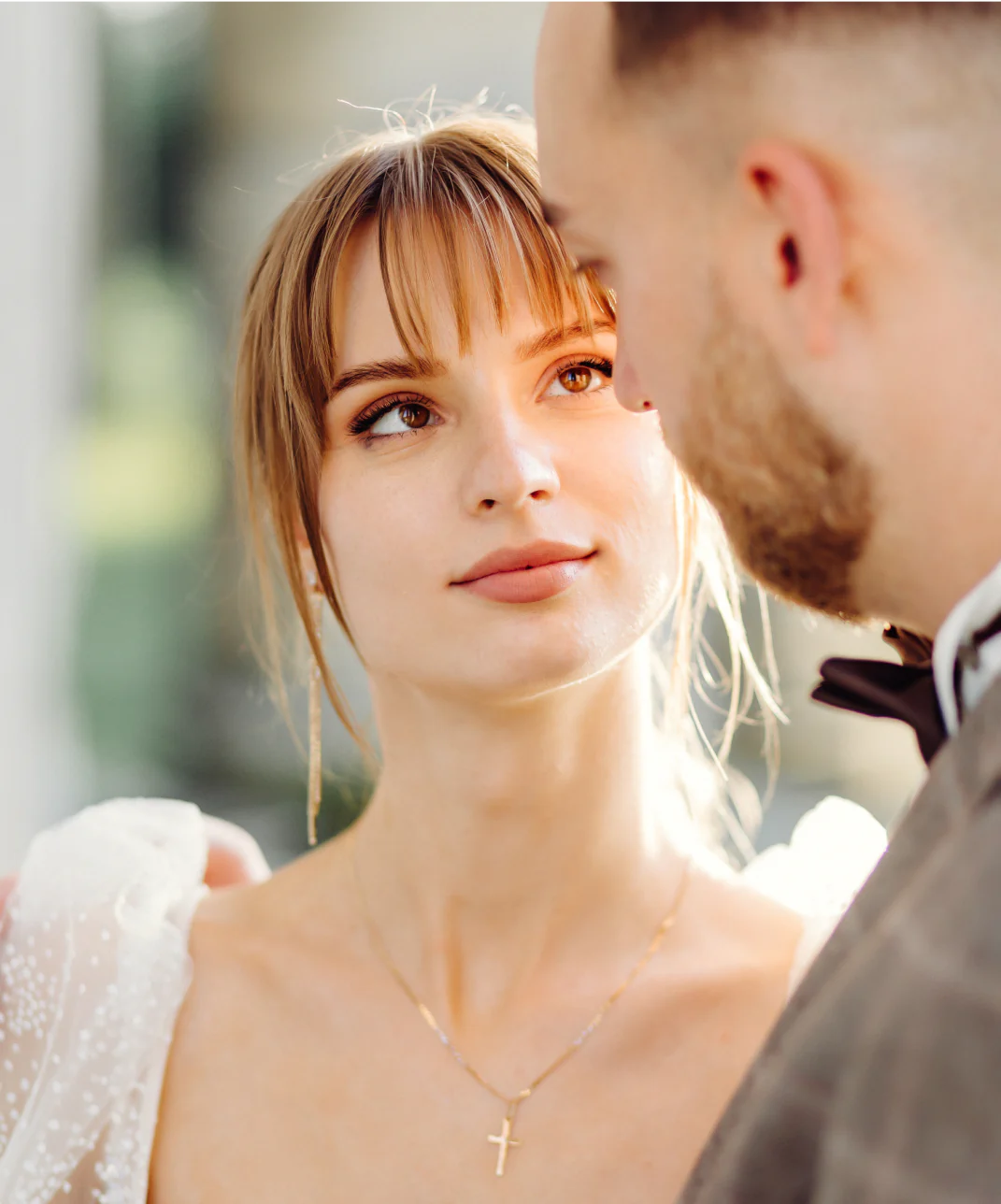 Blonde girl gazing into her boyfriend's eyes, showcasing a beautiful silver necklace.