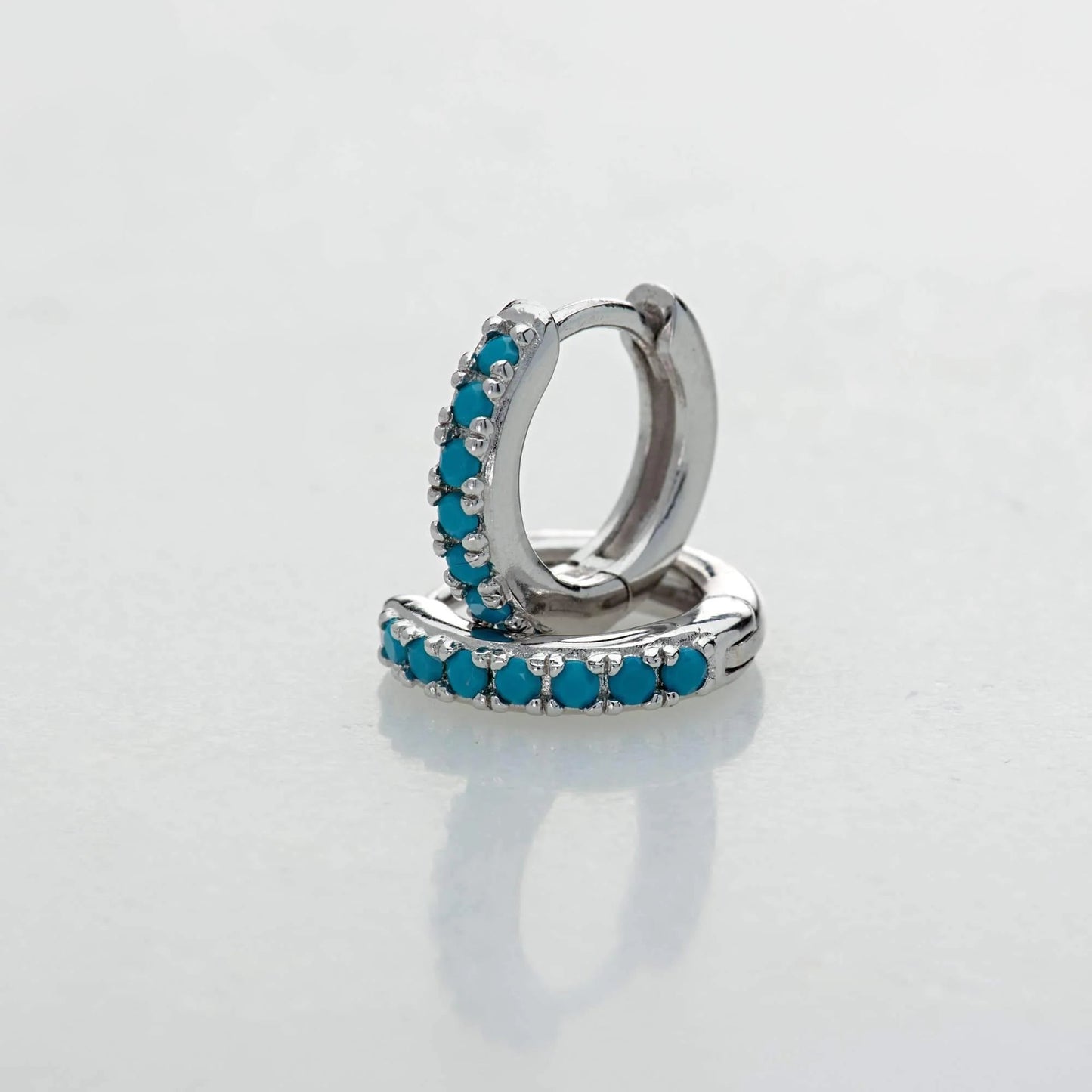 Silver Row Huggies Earrings with turquoise stones on a muted grey backdrop  - IceGlint