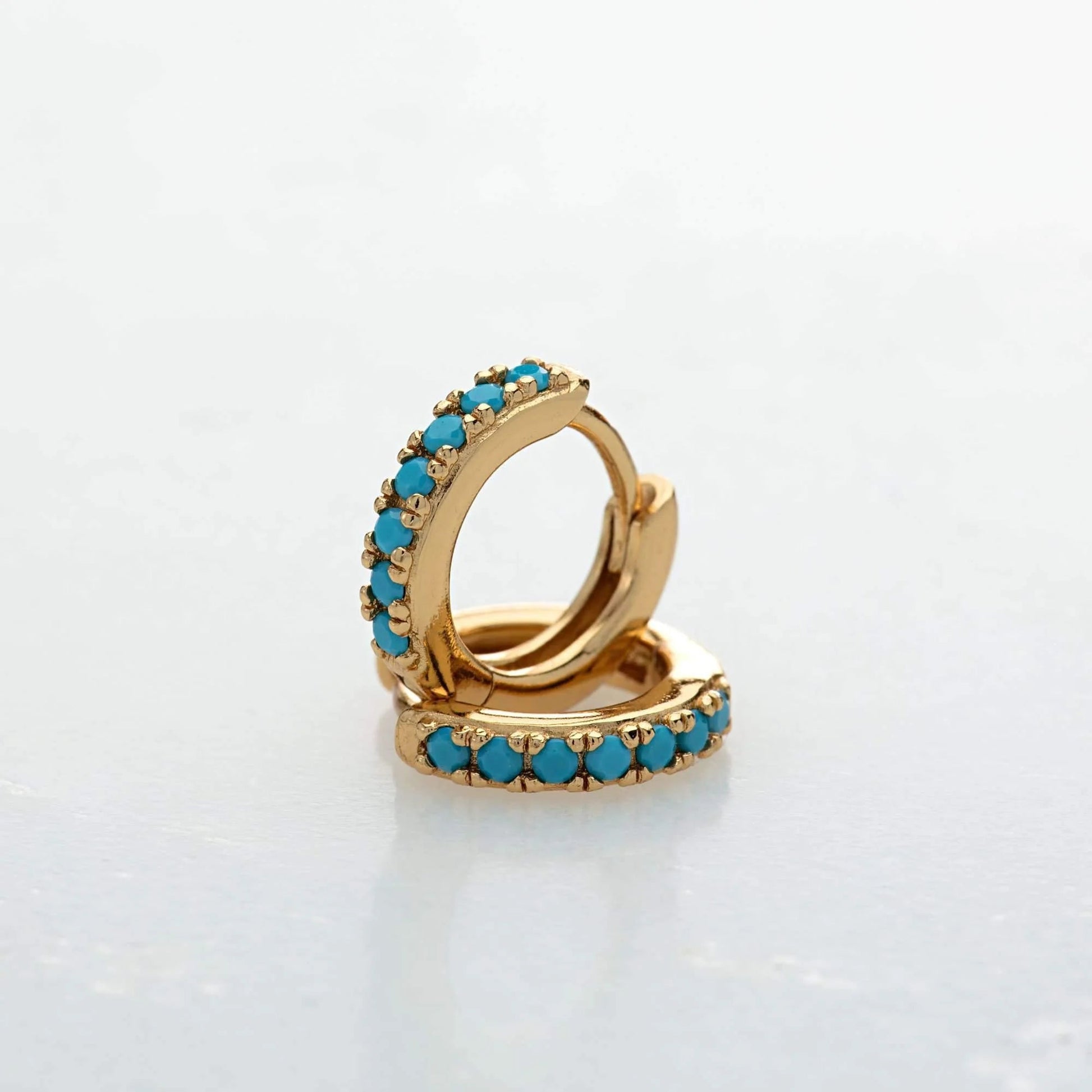 Gold Row Huggies Earrings with turquoise stones showcased on a grey background - IceGlint